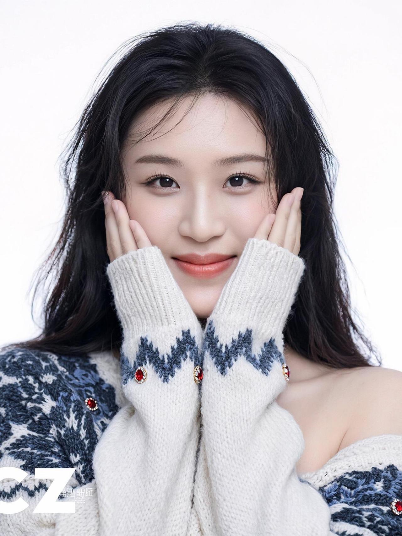 在这片柔软的针织纹理中，双手轻轻捧起脸颊，仿佛在守护一个秘密的梦。背景的纯净与主