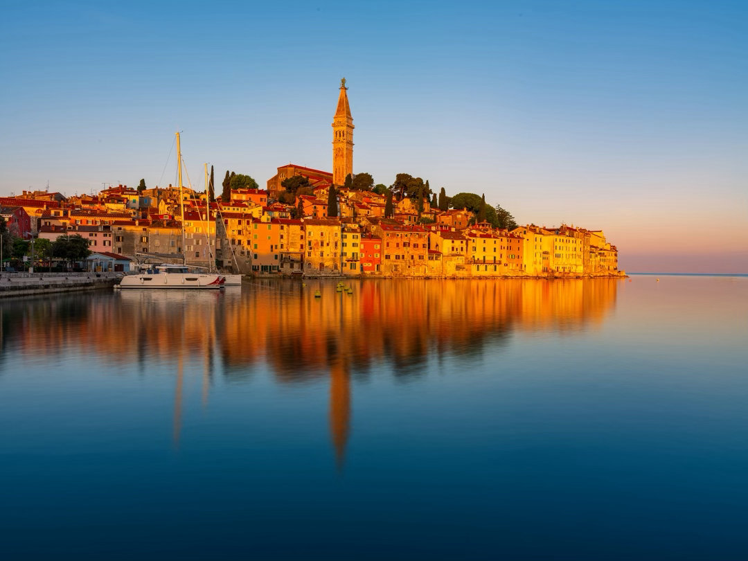 罗维尼的清晨，是蓝色的，也是金色的。朝阳落在古城的屋顶、钟楼和海面上，整座城被点