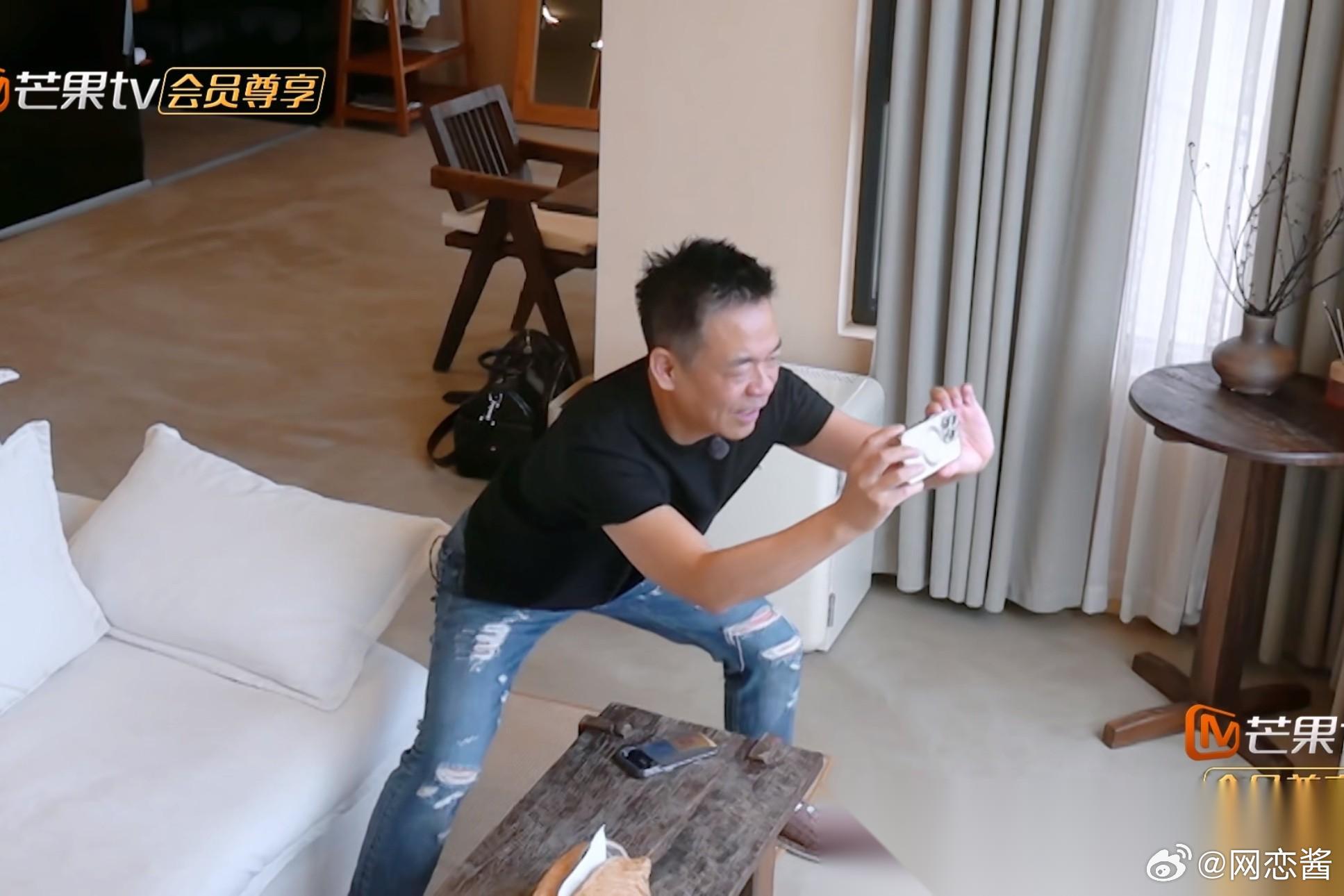 孙浩撅着屁股，拿着手机，自信满满地对戴军说：“我给你拍个很漂亮的照片哈～”一边拍