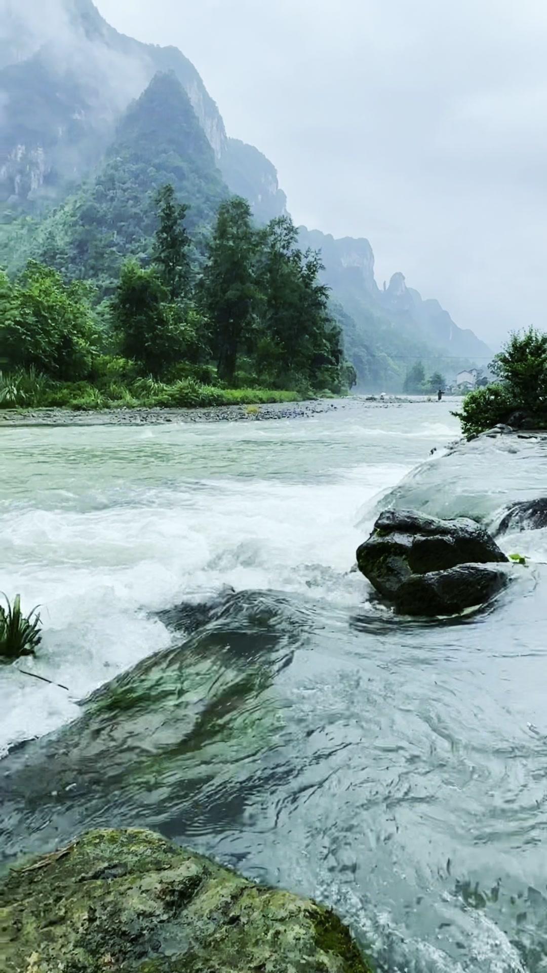 青石板路被雨水润得发亮，远山轮廓在烟雾中若隐若现。撑一把油纸伞，顺着水流慢慢走，