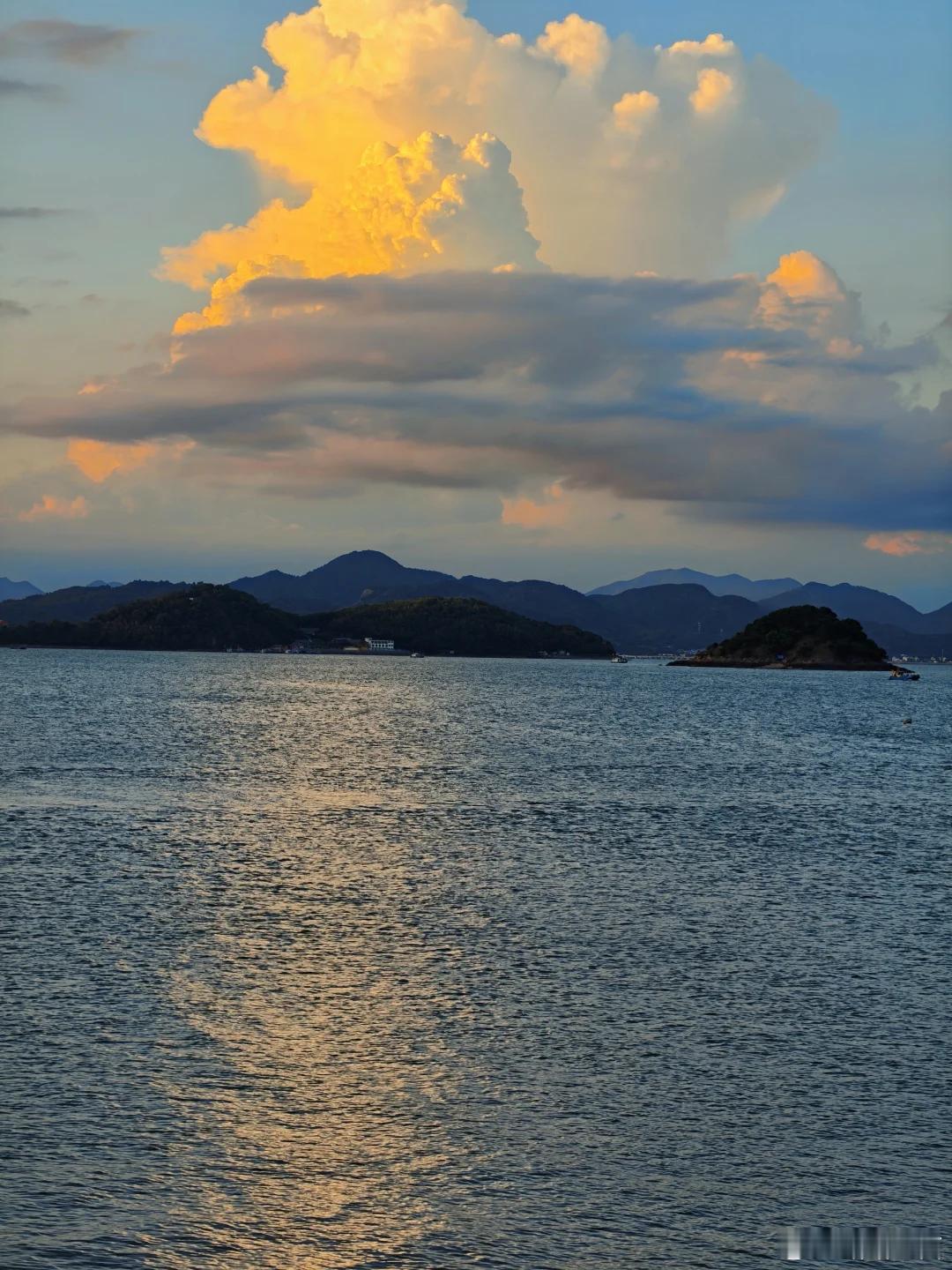 大朵云彩被落日染成金橘色，波光粼粼，山海氛围感十足 ​​​