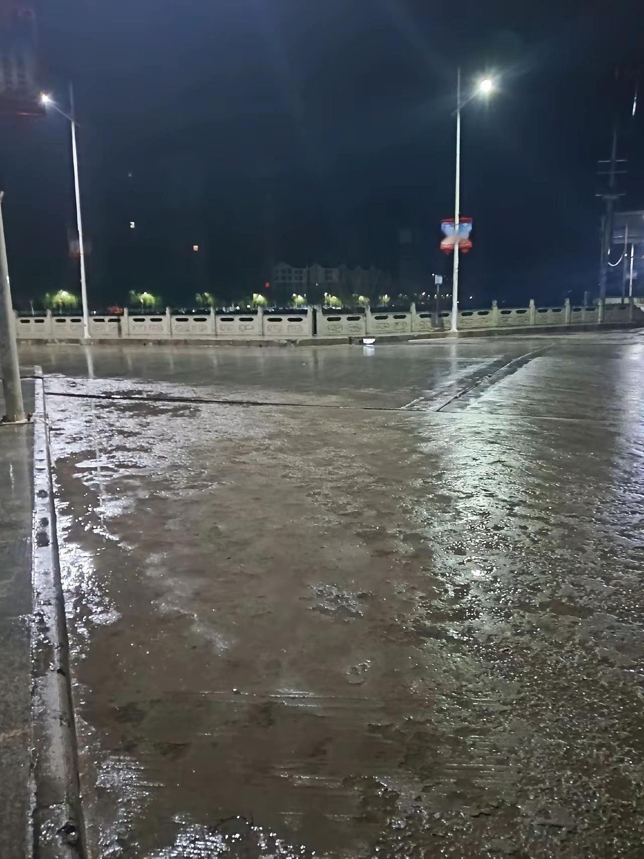 夜晚的街道，灯火阑珊，雨后积水，静谧而美丽。