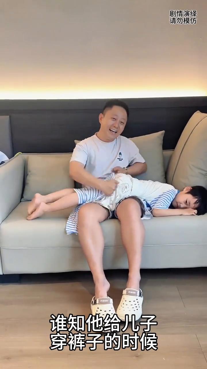 爸爸看电视入迷给儿子穿裤子整错了。
爸爸带着儿子在客厅看电视，谁知他给儿子穿裤子