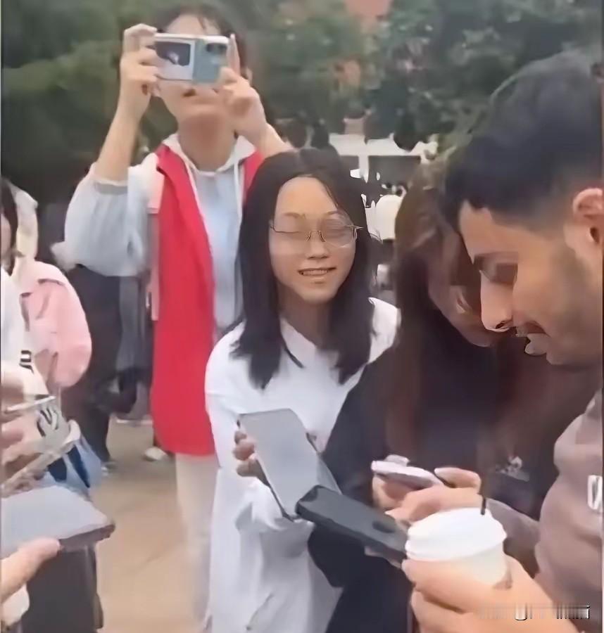 河北某大学门口，一排女学生举着手机要加几名外国留学生的连线方式，周围人看的都不理