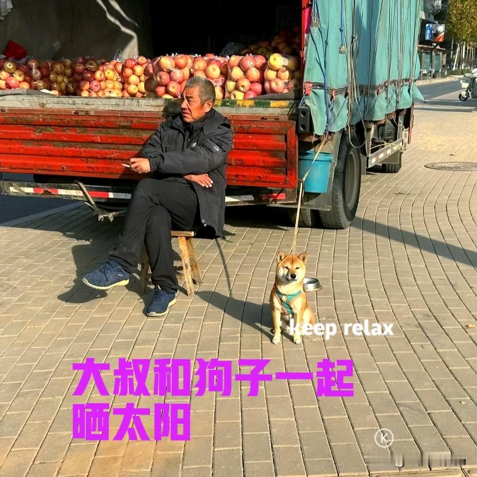 下午在小区的附近，看到一位卖苹果的大叔，悠闲地坐在凳子上，一边抽着烟一边晒着太阳