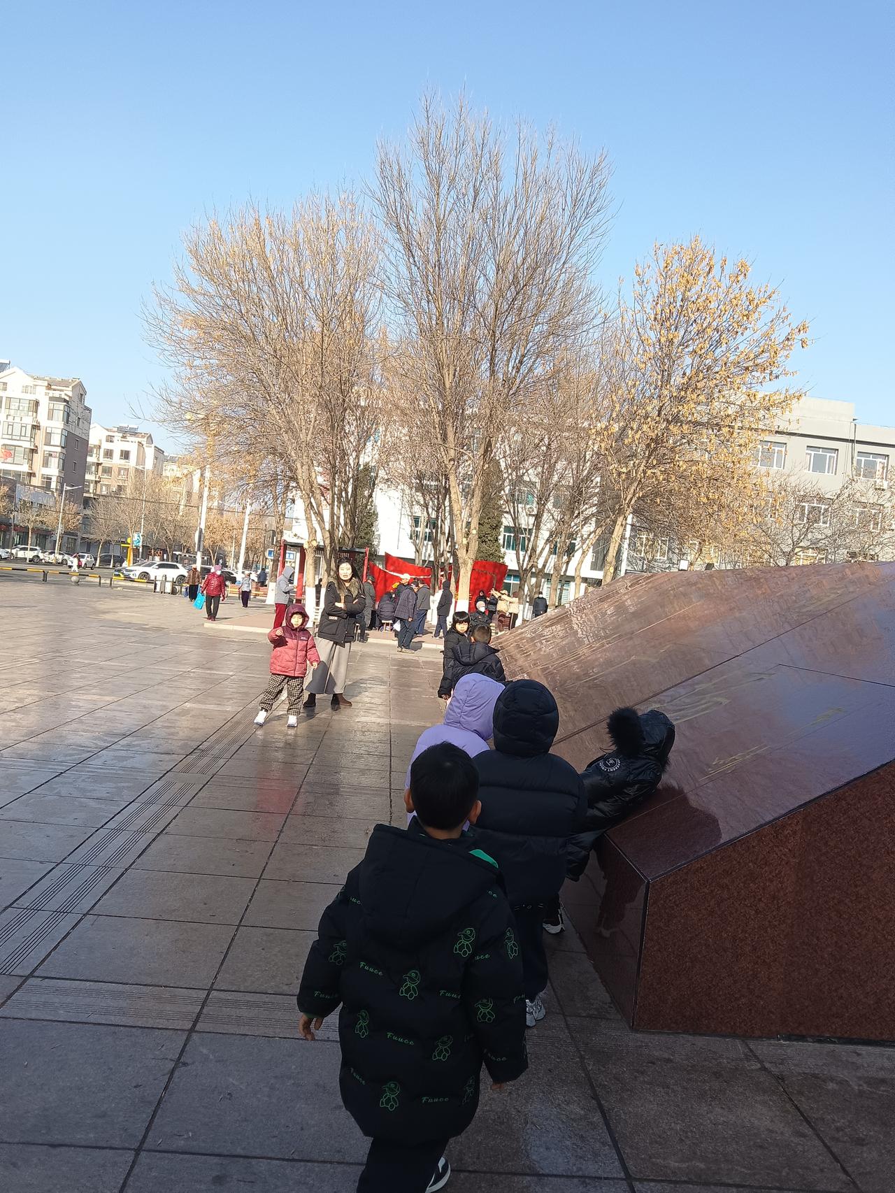 冬日暖阳下，孩子们在广场上欢快地奔跑，享受着无忧无虑的童年时光。