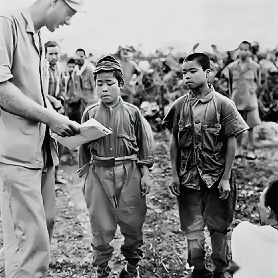 1945年，冲绳战役期间，两名被美军俘虏的日本娃娃兵，镜头中他们穿着极不合身的军