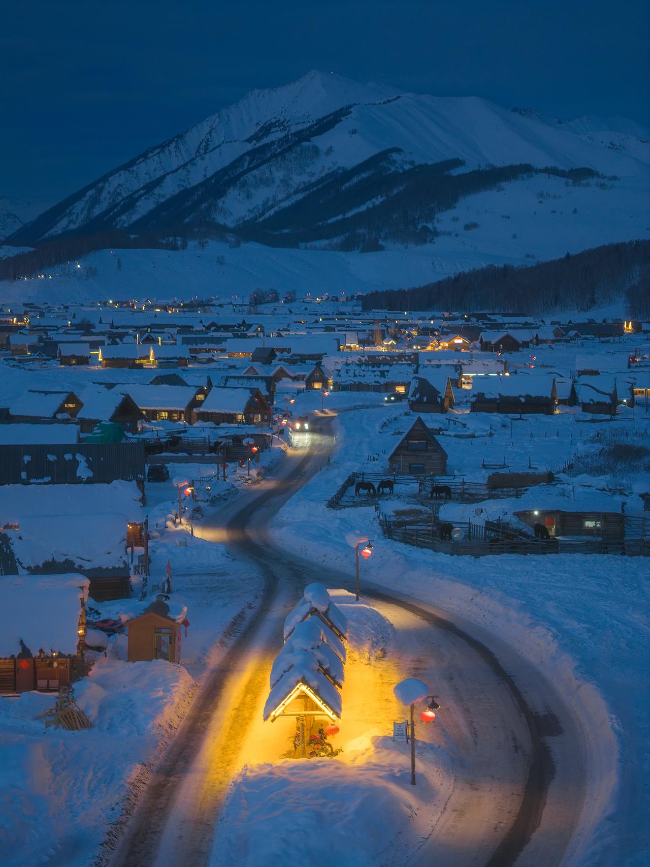 冬季新疆禾木的公交站台，温暖的灯光和蓝调时刻冷色的雪景形成了童话般的反差。

拍