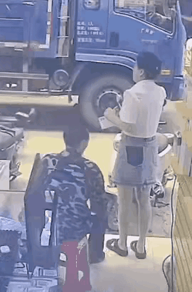 一名穿牛仔裙的小姐姐正在店门口打电话，坐在她身后的大叔，突然掏出打火机，直接把小