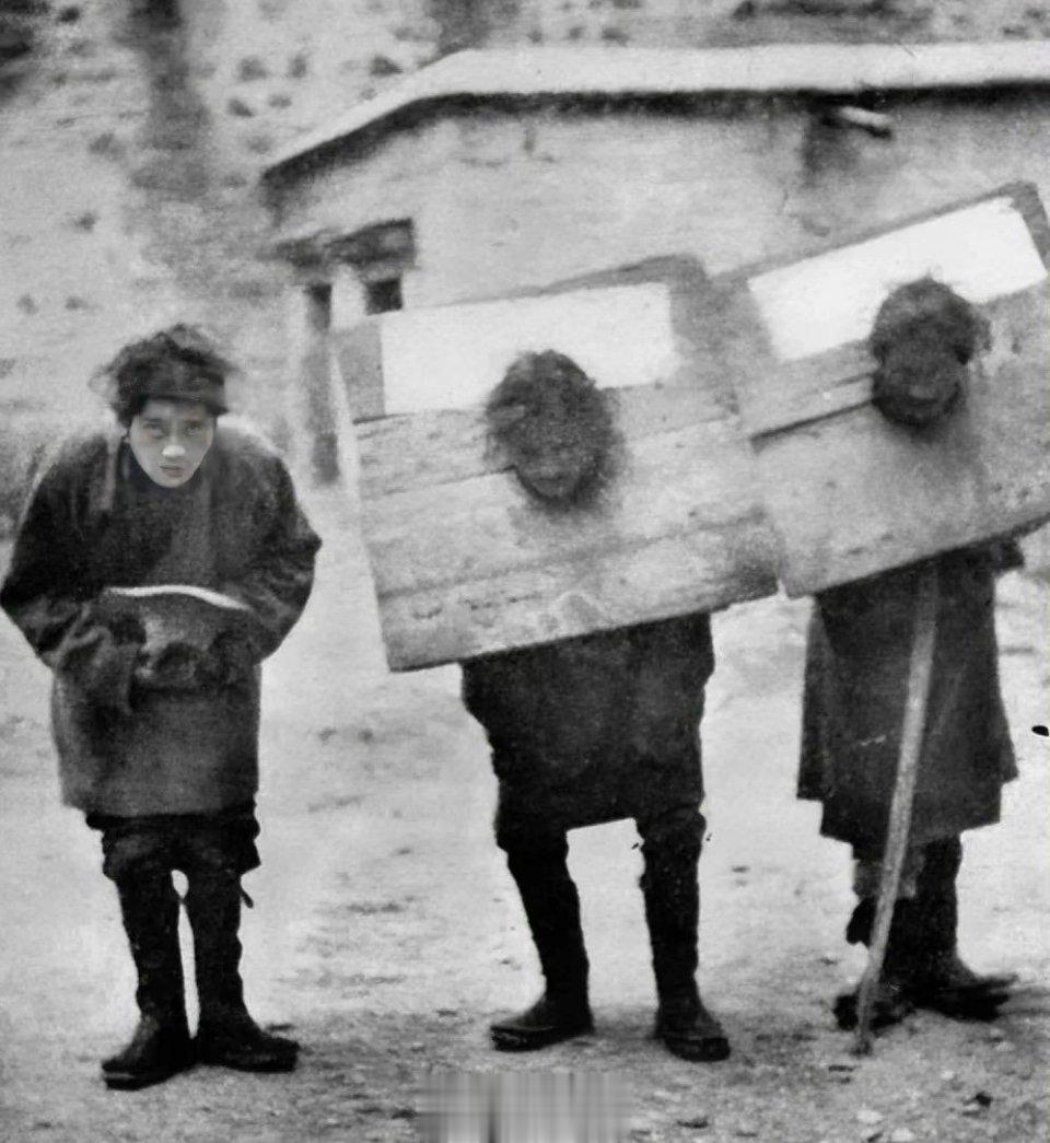 西藏未解放前几名农奴头上戴着厚重的枷锁，一脸凝重的望着镜头。当时他们的生活无比凄