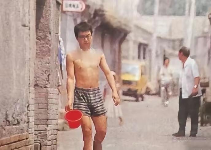 这个光着膀子，只穿一条横纹短裤，手里端着尿盆，行走在北京胡同里的男子是谁？