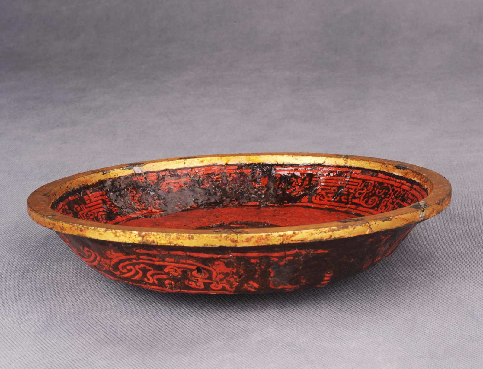 贵州省博物馆藏1959年清镇县新桥汉墓出土的朱绘夔纹海潮纹漆饭盘，盘背面锥刻汉隶