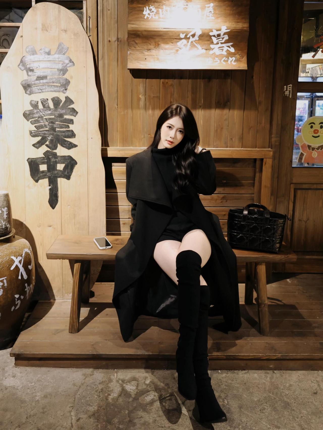 在夜色中，她静坐街角，
黑色大衣，包裹着孤独的灵魂。
长靴踏过岁月的门槛，
每一