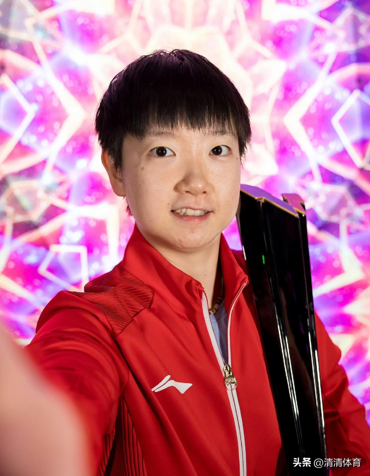 手捧美国大满贯女单冠军奖杯的孙颖莎身着鲜红队服，暖金光影衬得画面温柔大气。
她稳