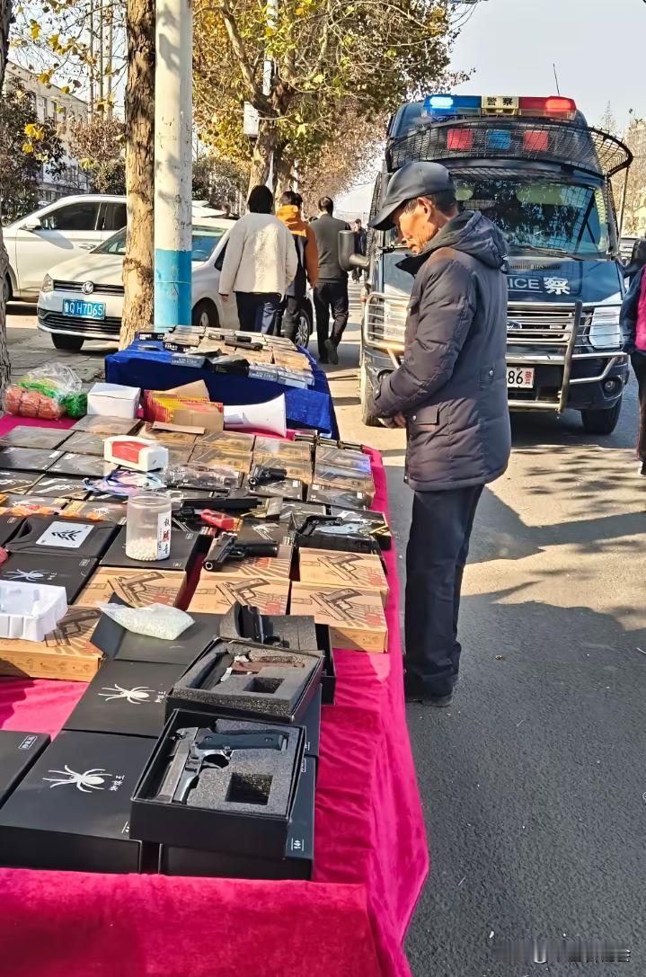 一名男子竟然在街头摆摊公开贩卖各种仿真枪玩具？
更奇葩的是就在不远处还停着一辆警