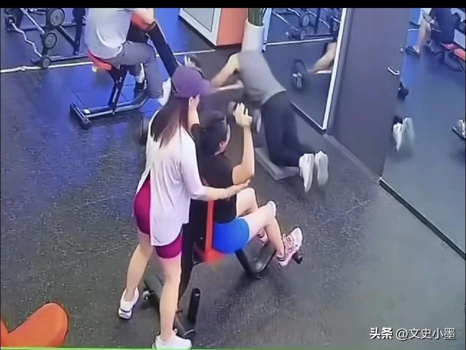 一男子在健身房健身时，旁边两位美女一直在瞅他，嘴里不停的在说些什么，突然，穿蓝色