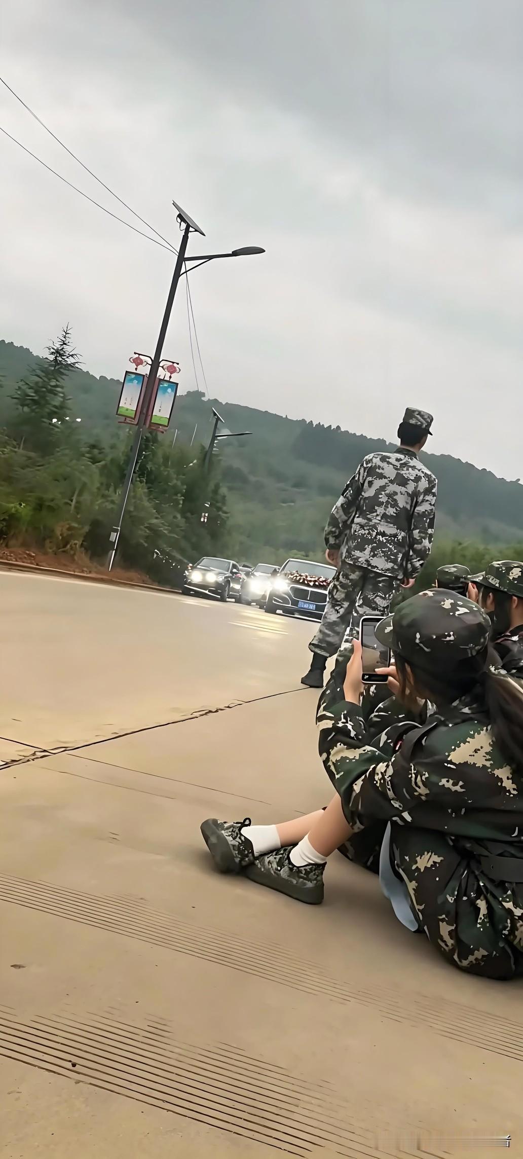 云南昆明，大一新生正在进行军训拉练，队伍中途休息时，路上偶遇一支婚车车队。
 