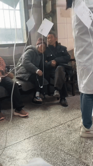 老爷爷陪着生病的老奶奶在诊所里输液看病。
老奶奶依畏在老爷爷的肩膀上，这画面真是