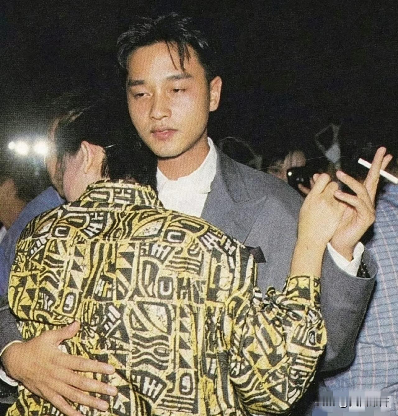 烟灰抖落半截，那件灰西装箍着人晃来晃去。灯光打得脸红红的，手搭在姑娘腰后，整个人
