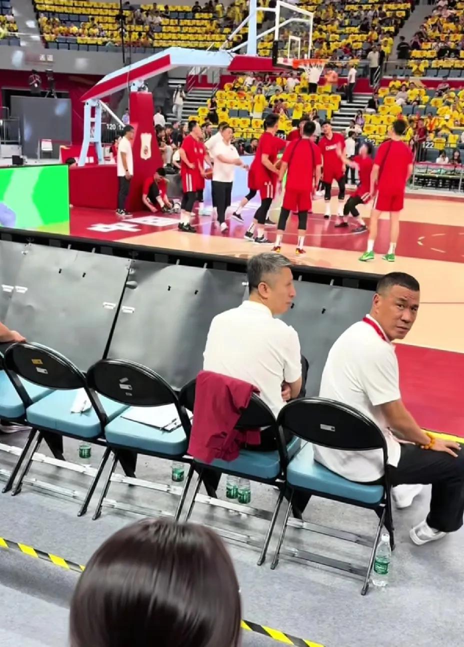 中国男篮正在热身，主教练郭士强坐在场边观看，这时郭士强身后不远处一个球迷朝他喊话