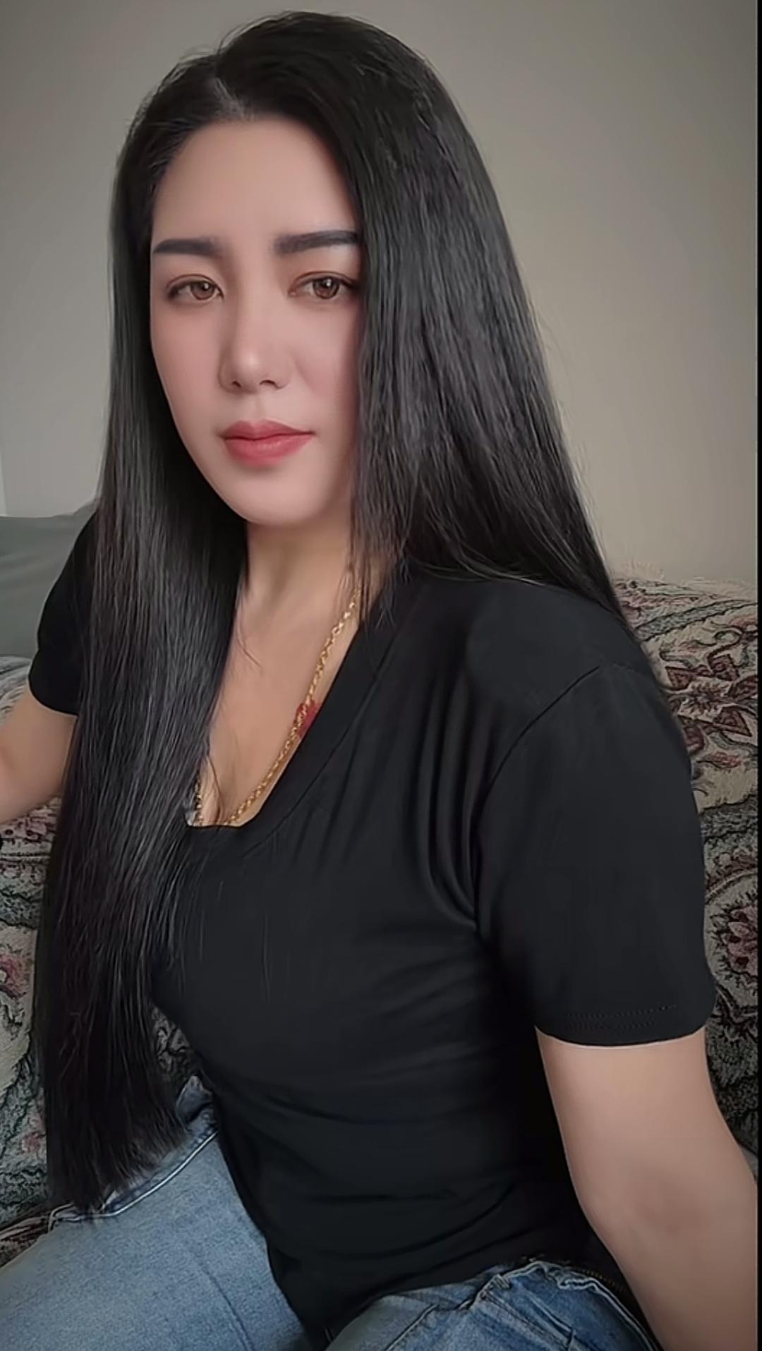 长发美女坐在沙发上，穿着黑色T恤。