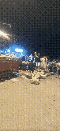 男子把西瓜高高举起，重重地摔在摊主的头上，一连摔了多个西瓜，摊主始终坐在那里，任