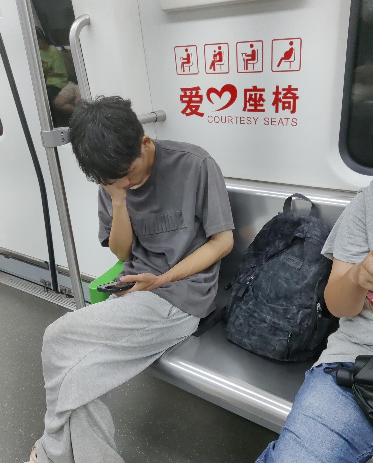 看这个年轻人，
鞋子有点脏，
他把包放在爱心座位上，
地铁里还有很多人站着，
没