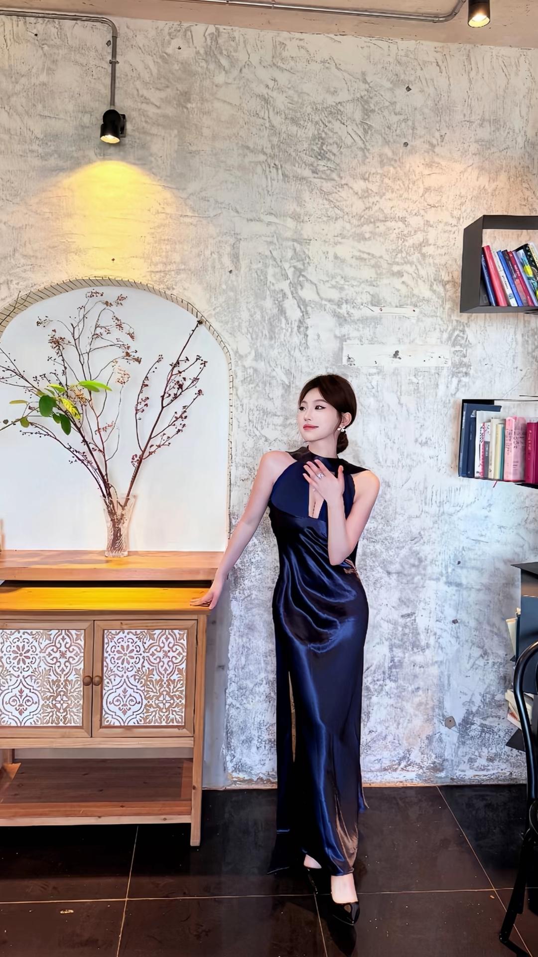 你身着一袭深蓝丝缎长裙，宛如从古典画卷中走出的绝代佳人。裙摆轻曳如流水般灵动，领