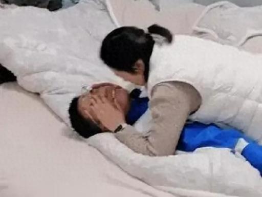 男孩躺在床上，一名女子压住他的上半身，双手捏着他的脸，不停追问：“服不服？”
