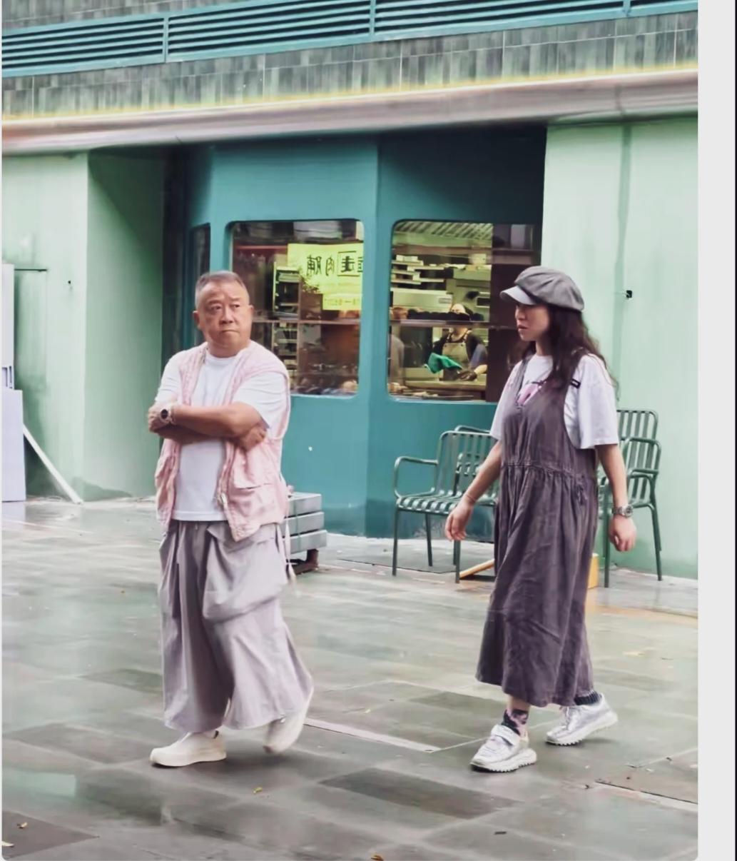  脱离荧幕包装的曾志伟穿搭宽松休闲，身形矮胖，身高明显低于身旁女士！
画面中两人