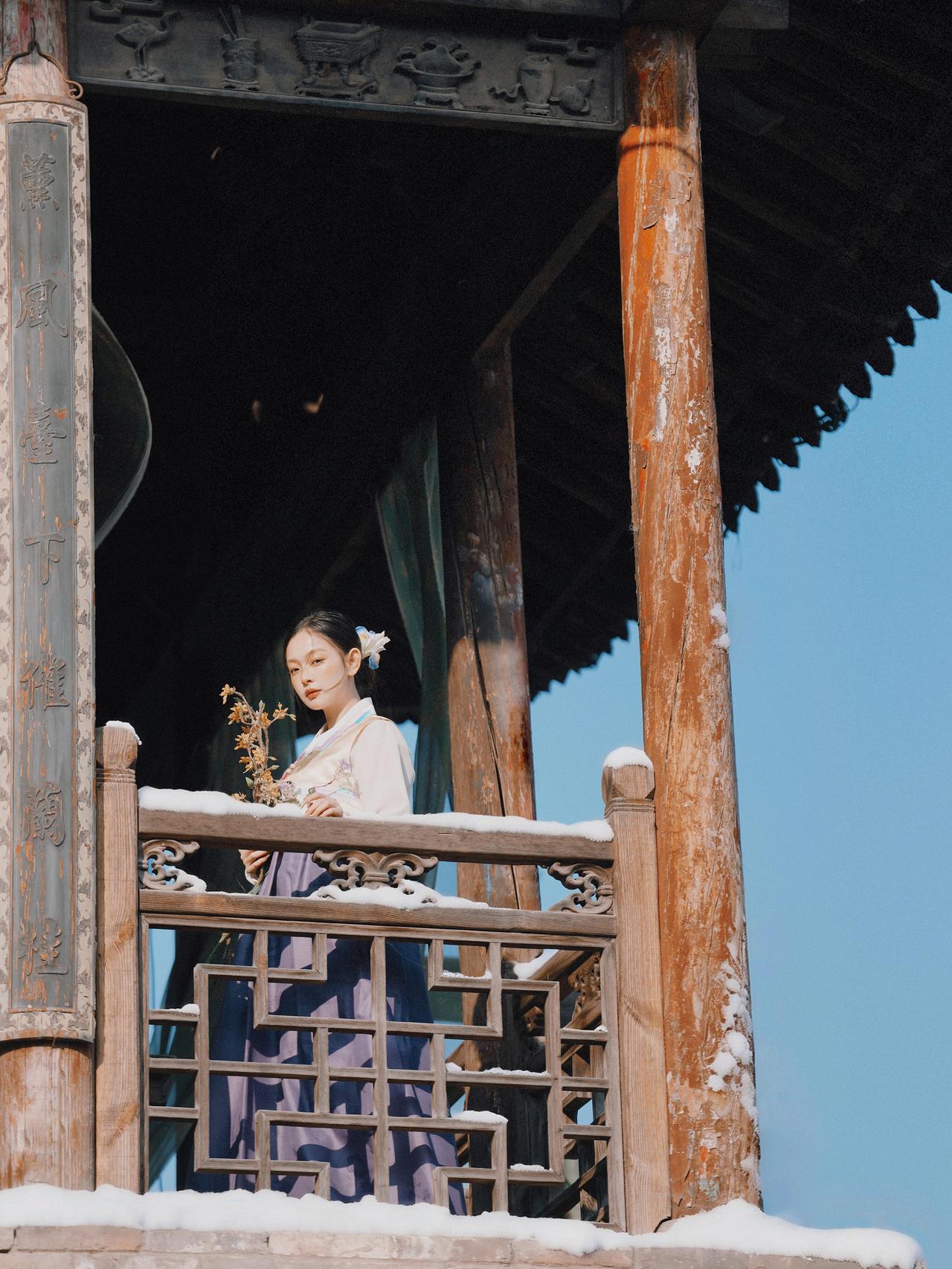 这张坐像以古建木窗为背景，几何窗格纹理与人物服饰的柔美线条形成鲜明对比。暖调侧光