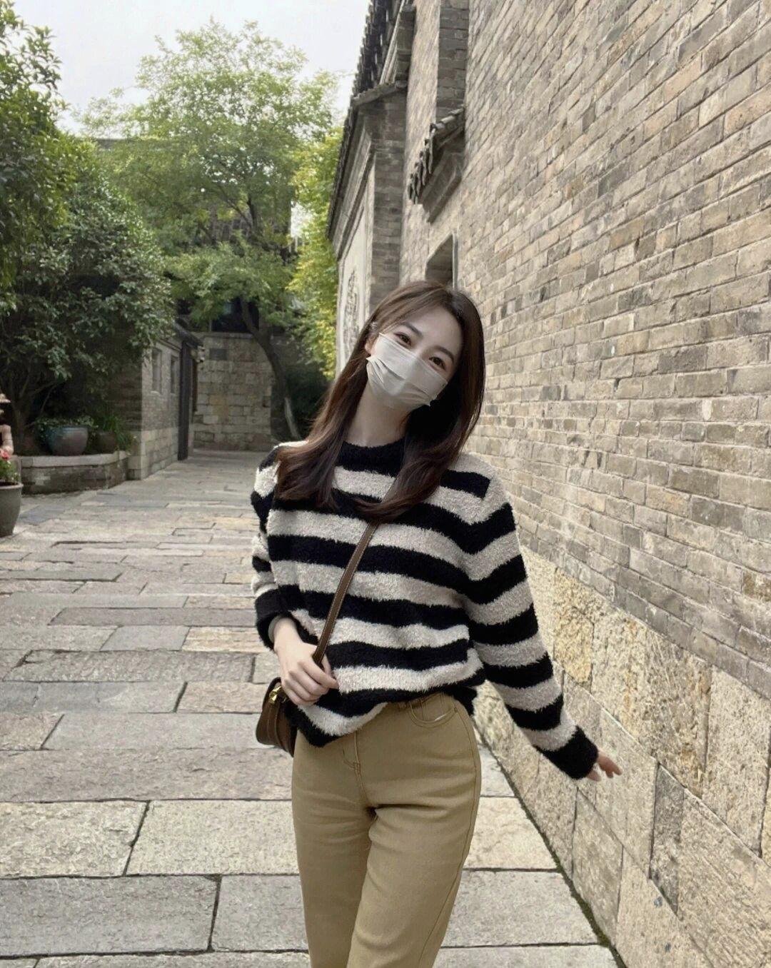 黑白条纹毛衣搭配米色裤子，走在古朴的石板路上，感受时光的静谧。