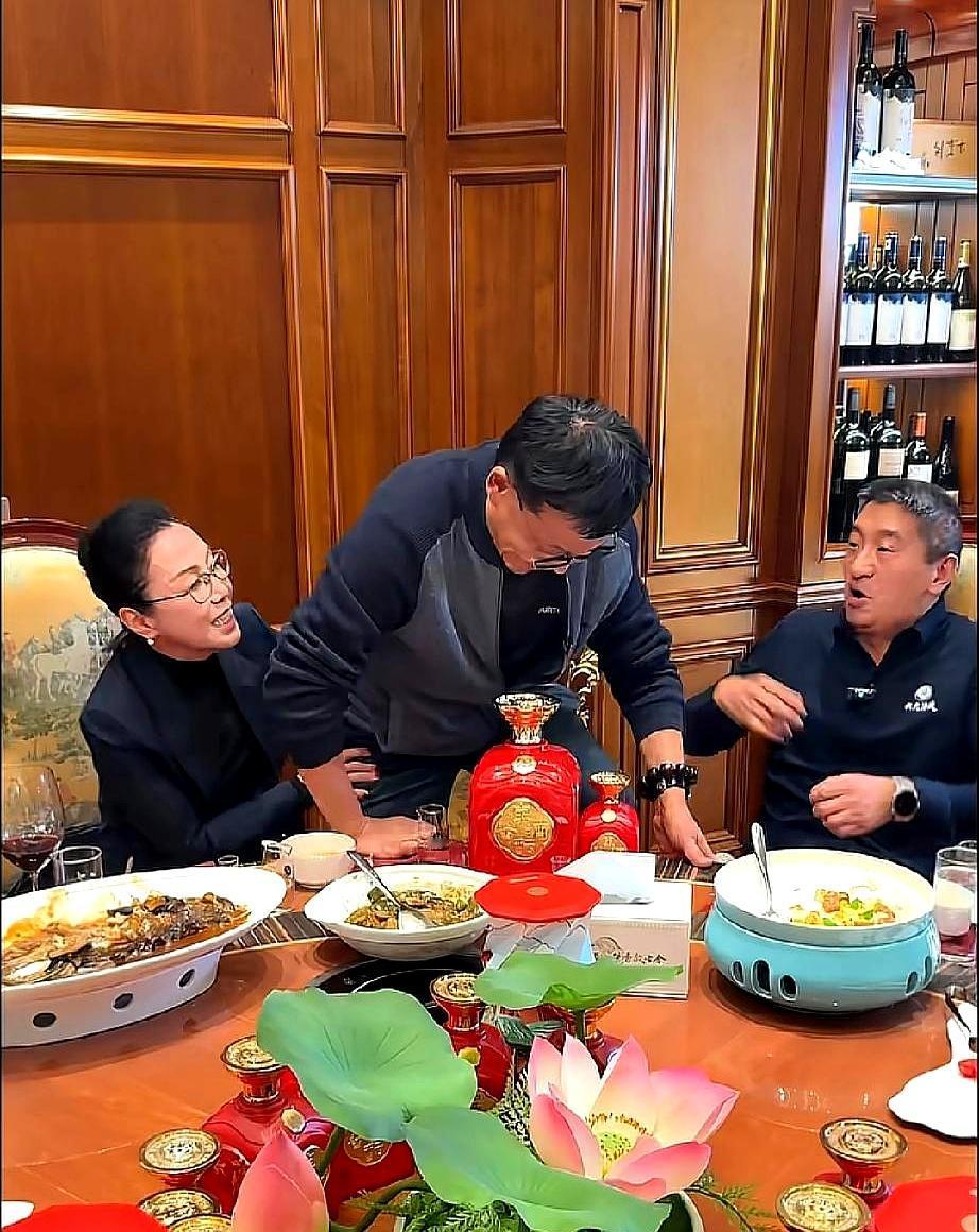 朋友局上，他双脚踩在椅面，半蹲托着碗，边演示边吃，旁边的张丹红伸手去扶，腮帮都涨