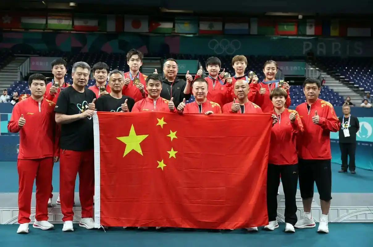 国乒教练员手擎国旗与夺冠的球员们大合照：李隼高大修伟，王皓笑若朗月，秦志戬风度翩