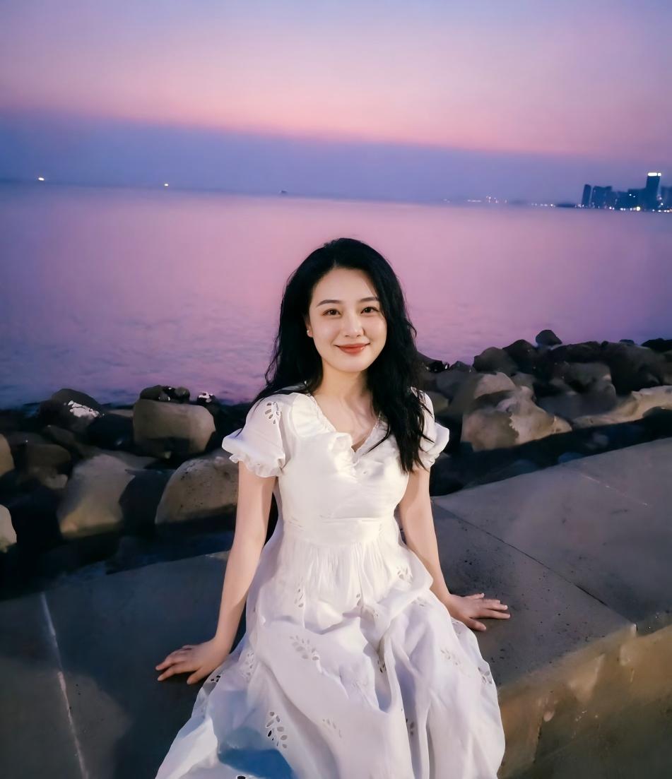 夕阳下，她坐在海边微笑。