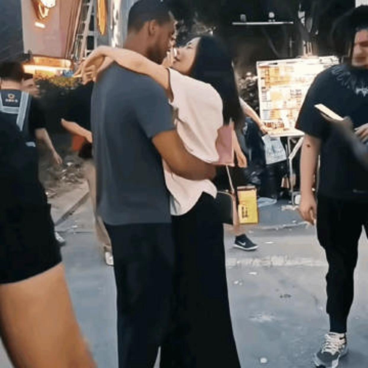 一名中国女子与一位非洲黑人男子在闹市区大街上旁若无人的拥抱亲吻在一起，刚开始，两