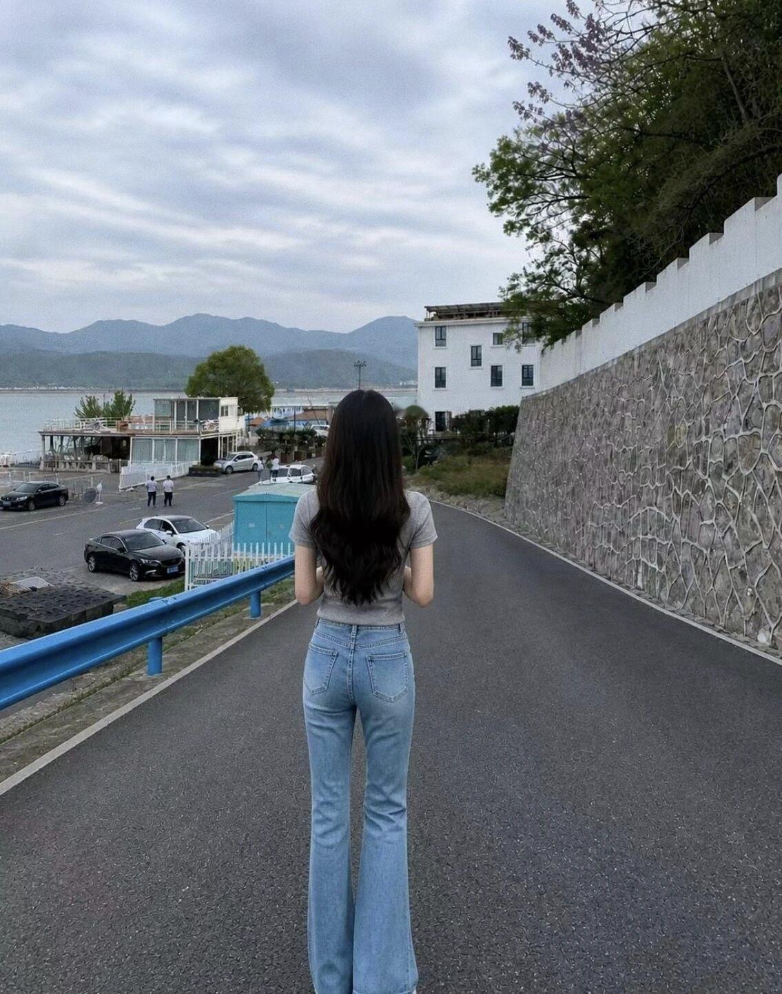 背对镜头，眺望远方，感受海风拂面的自由与宁静。