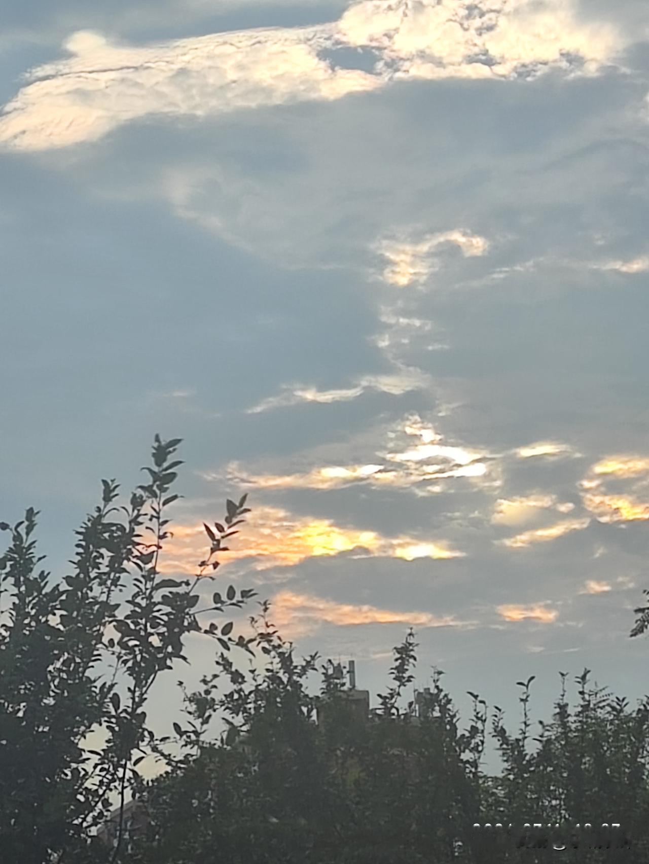 傍晚时分抬头撞见温柔晚霞，云层被落日晕开淡淡的金橘色，灰蓝天幕衬得柔光格外治愈。