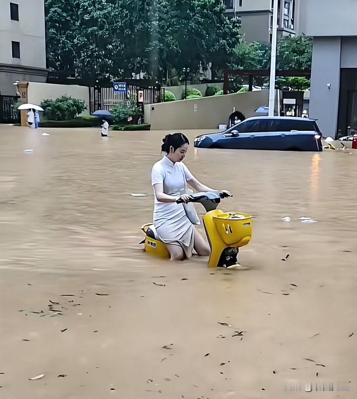 广西，暴雨内涝，街道积水没过膝盖，一位穿旗袍的女士硬是骑小黄车涉水出行，视频底下