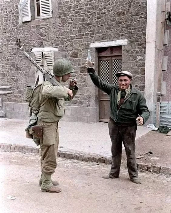 1944年7月，在法国诺曼底的库唐斯，一名法国当地的老百姓向一名美军机...