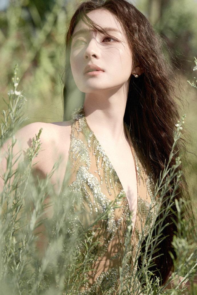 鎏金绣羽裙漾开碎光，垂坠长发揉进绿植清氧——她栖身于温室与郊野的交界，或抬眸撞进
