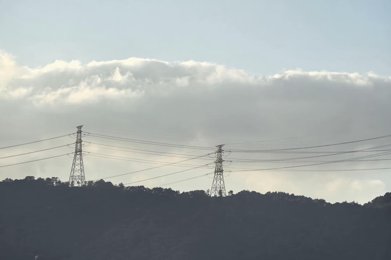 山峦静默，铁塔如诗，云海翻涌间，是自然与工业的温柔对白。山巅的塔影与流云共舞，静