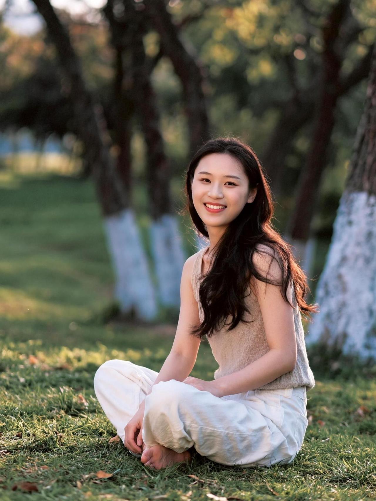 她坐在阳光洒落的草地上，笑容如微风般轻柔，仿佛在低语：“生活不需要太多装饰，有阳
