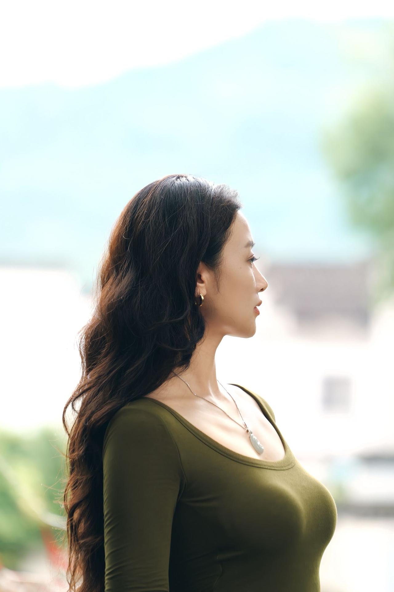 女人真正的气质是什么？青灰圆窗框住古宅岁月，绿意衣衫撞入庭院清宁。老木窗棂藏着过