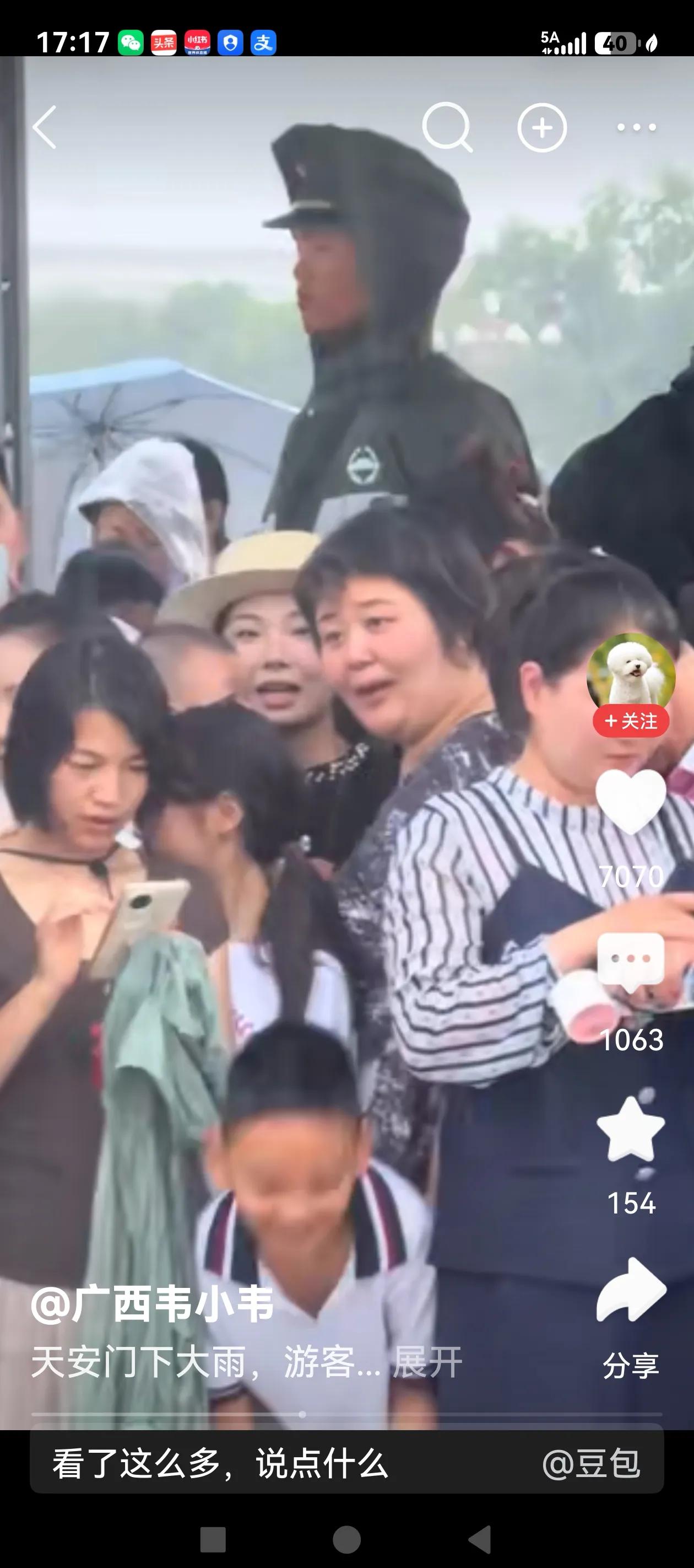 网友发了一条视频，游客到天安门广场游览，突降大雨，游客围拢在哨兵的周围避雨，这场