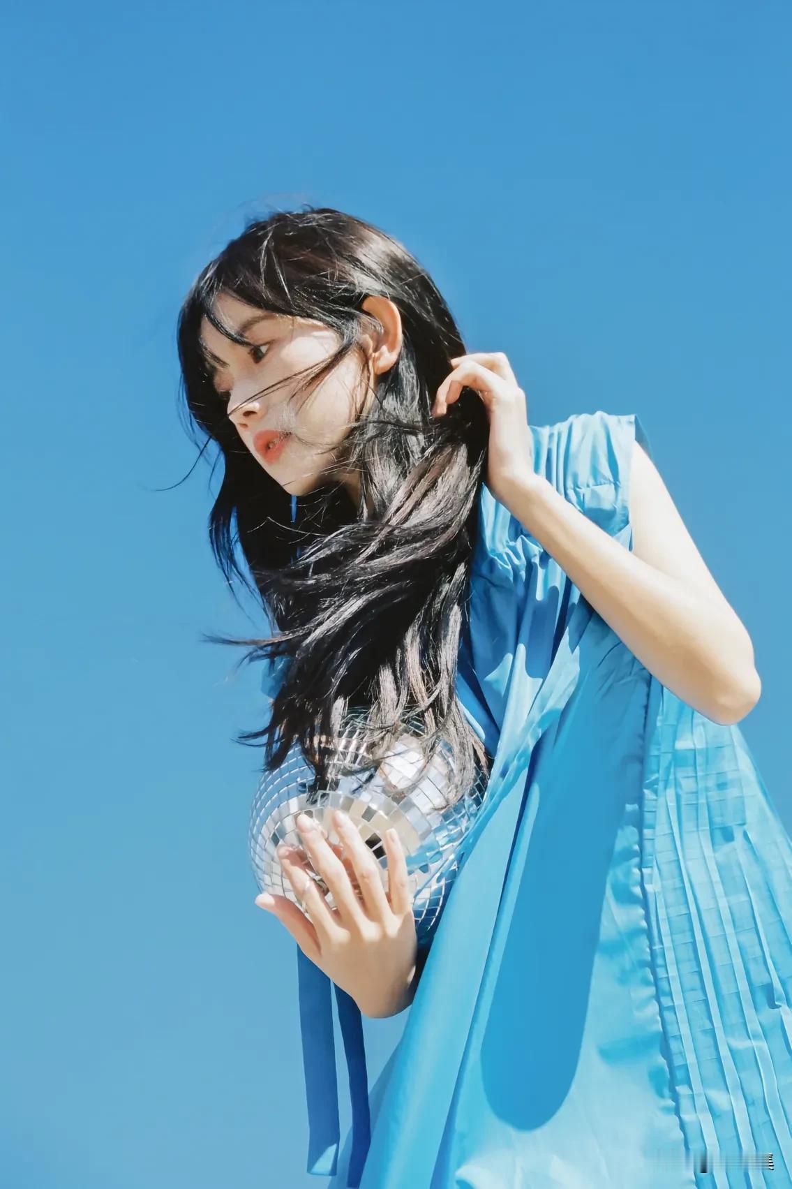 海边女孩穿蓝色裙，海鸥飞翔，阳光明媚。