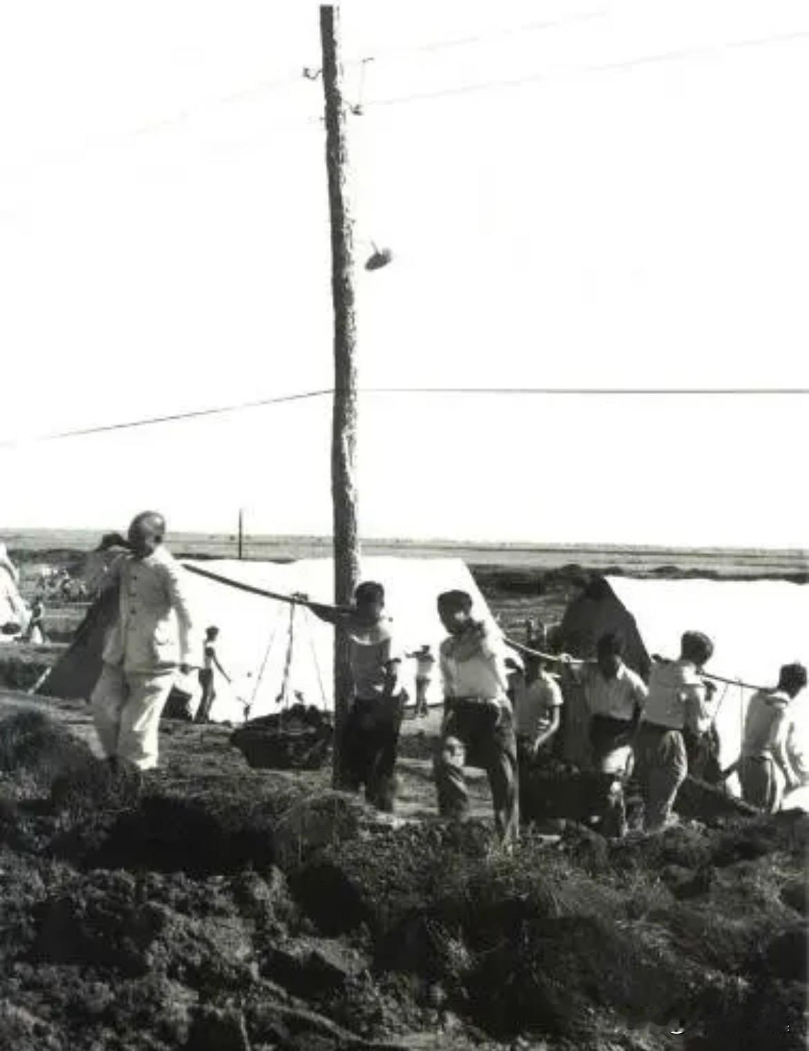 1958年，时任农垦部部长王震在黑龙江密山垦区云山水库工地参加劳动的老照片。王震