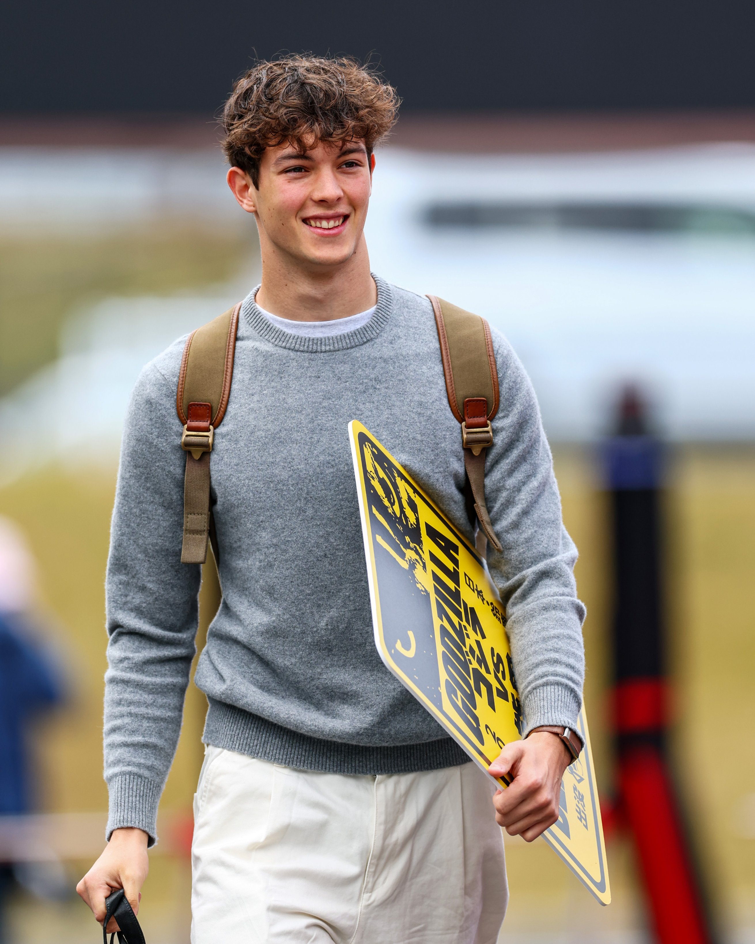 贝尔曼拿着“哥斯拉VS熊男”的牌子走进围场F12026F1日本大奖赛