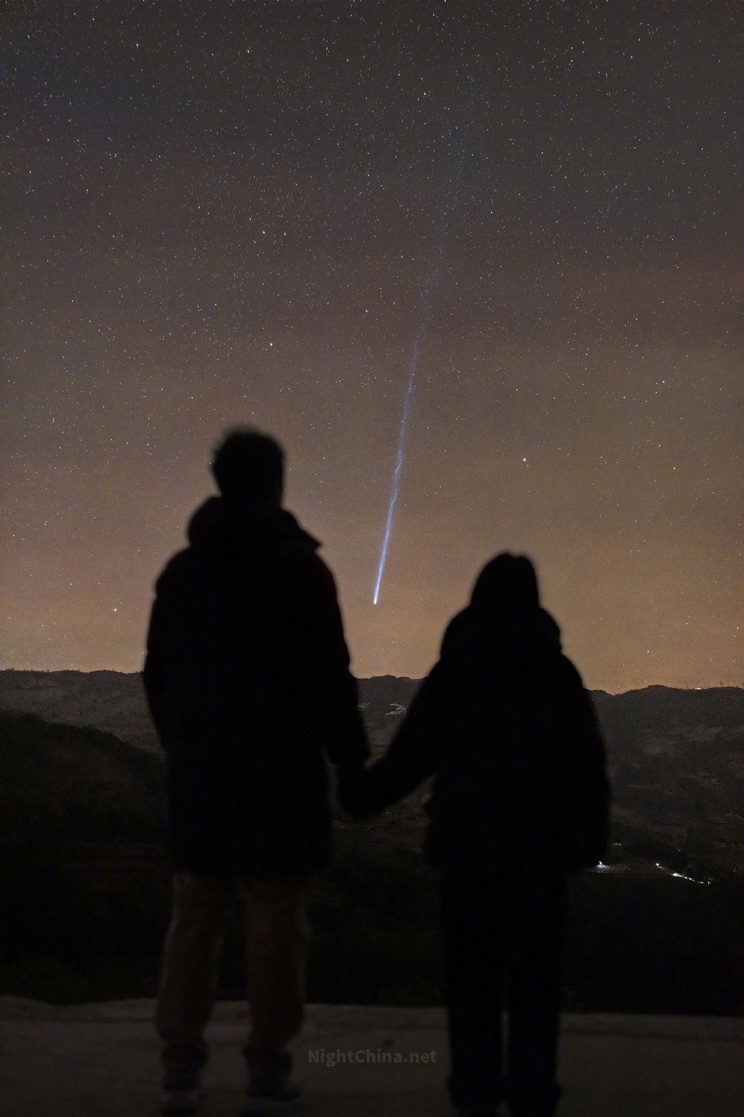 山下是人间散落的灯火，眼前是一颗正在升起的彗星。那长长的彗尾像谁在夜空里凝固的一