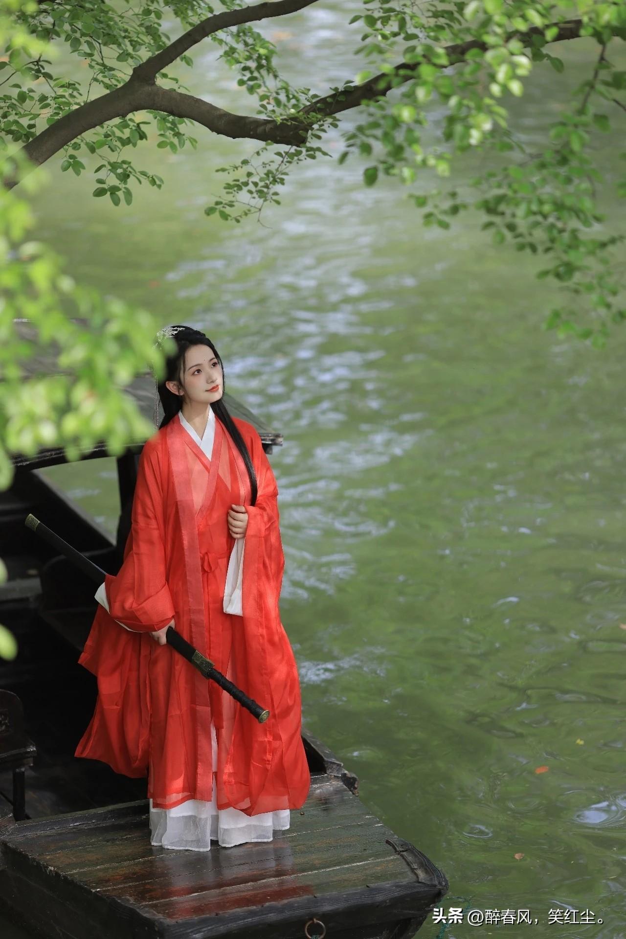像是从山水画里走出的仙子。
身畔是碧波荡漾的江水，
身后是连绵起伏的青山。
不需